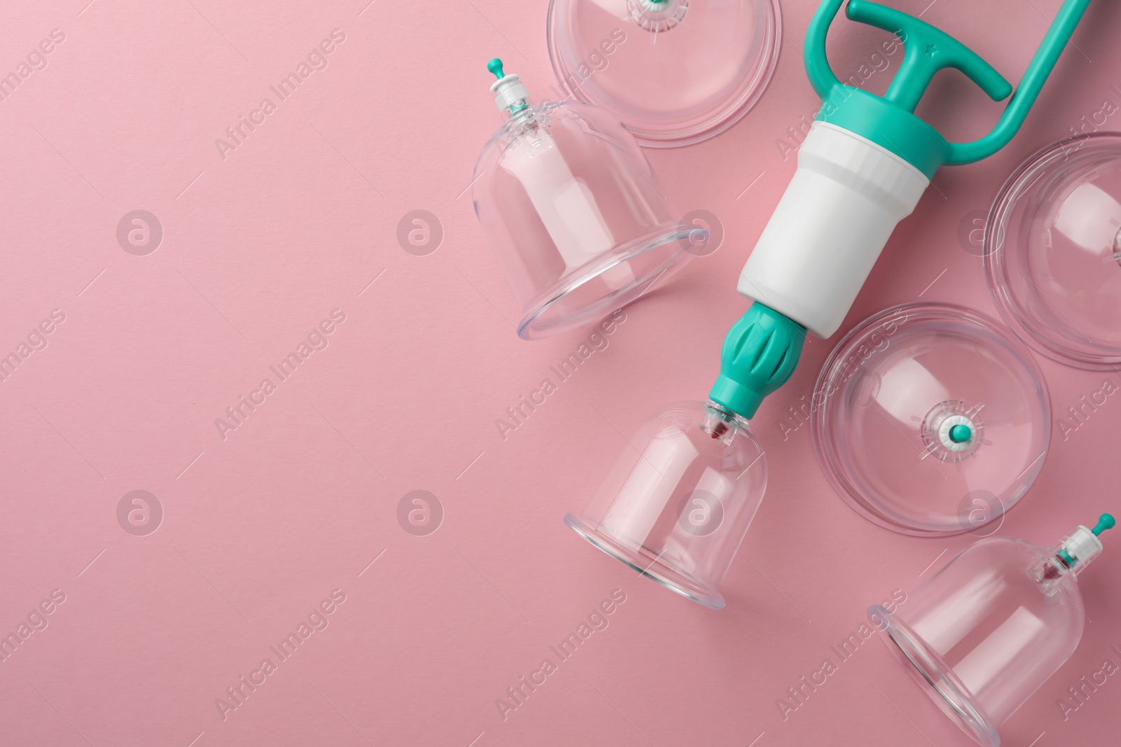 Photo of Plastic cups and hand pump on pink background, flat lay with space for text. Cupping therapy