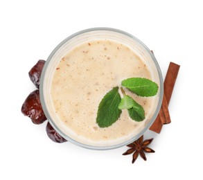 Glass of delicious date smoothie with mint, dried fruits, anise and cinnamon stick on white background, top view