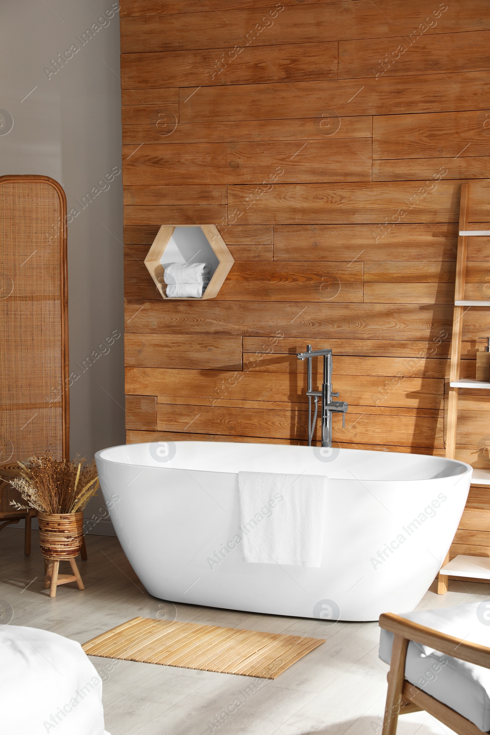 Photo of White tub and decor near wooden wall in room. Interior design