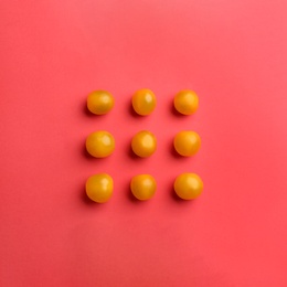 Photo of Yellow tomatoes on red background, flat lay