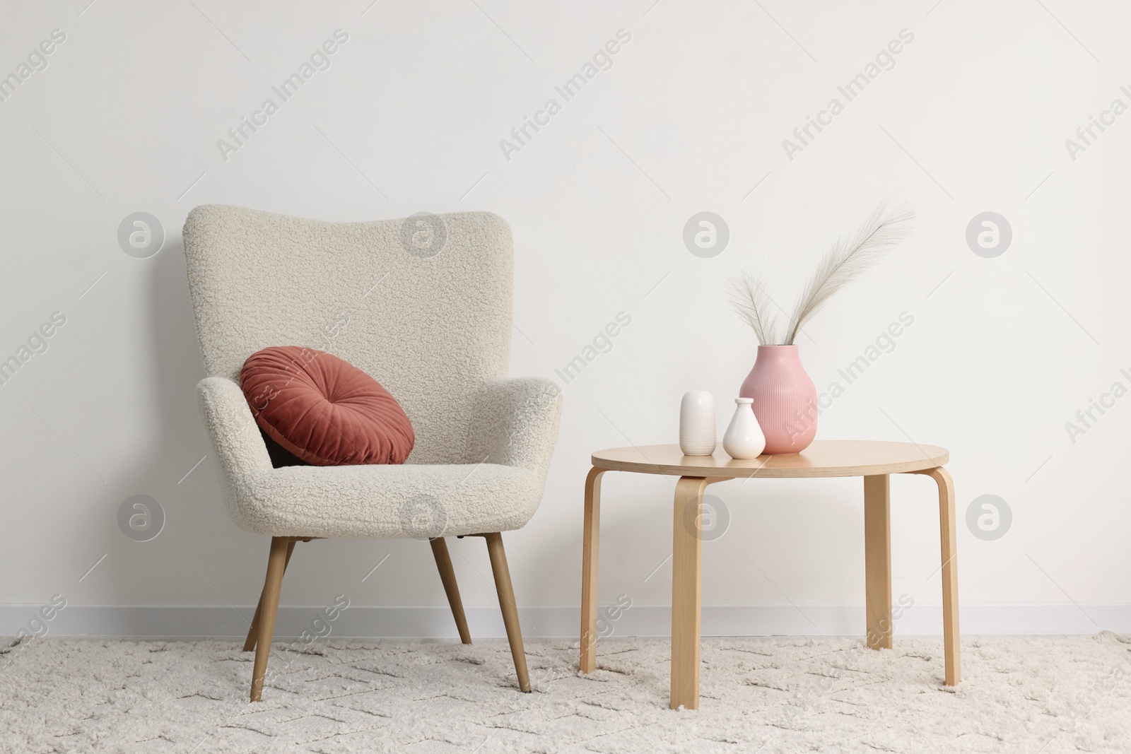 Photo of Comfortable armchair, pillow, coffee table and decor indoors