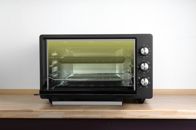 Photo of One electric oven on wooden table indoors