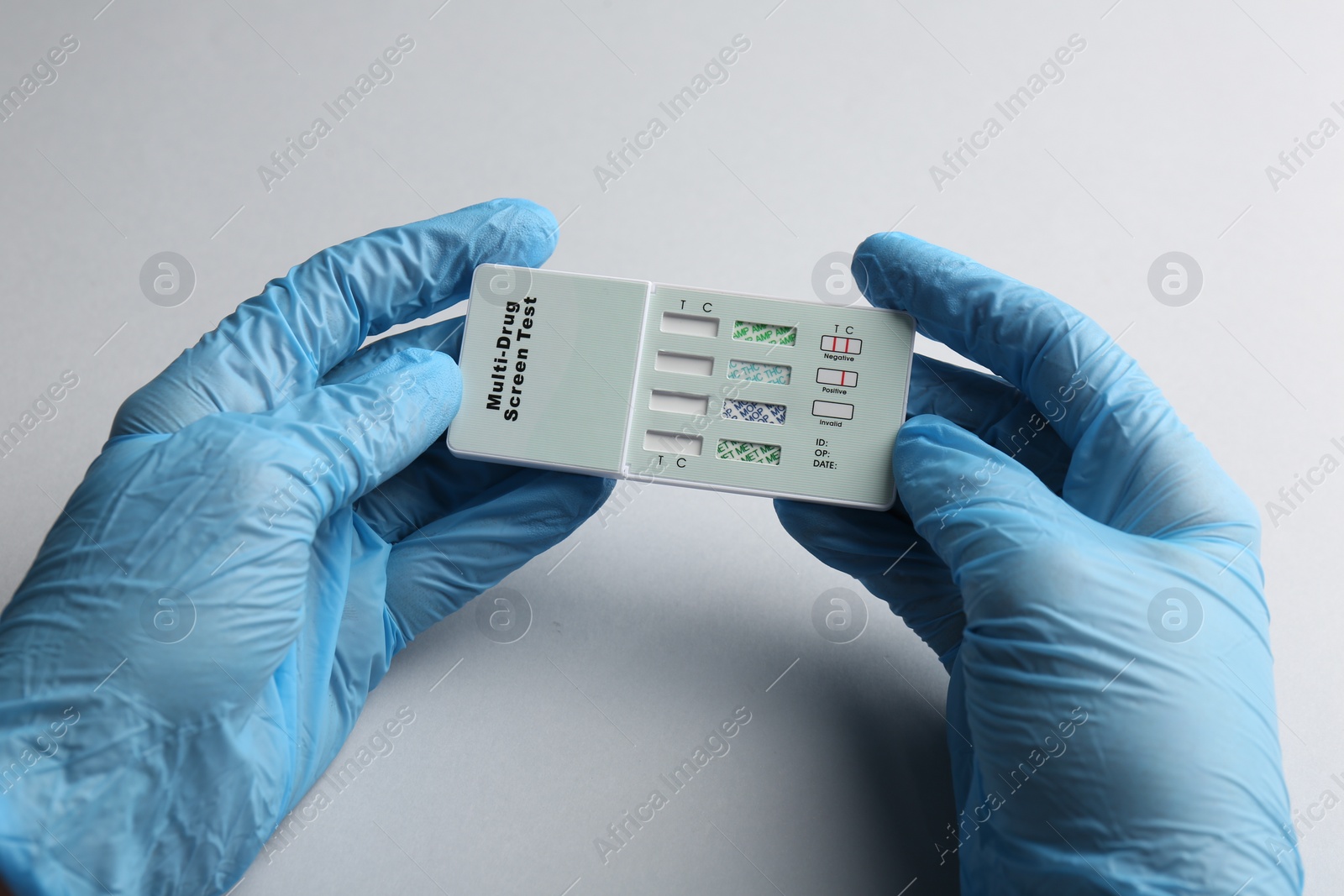 Photo of Doctor holding multi-drug screen test on light grey background, closeup