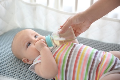 Photo of Lovely mother giving her baby drink from bottle in cot