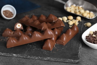 Photo of Tasty chocolate bars with nuts on black table