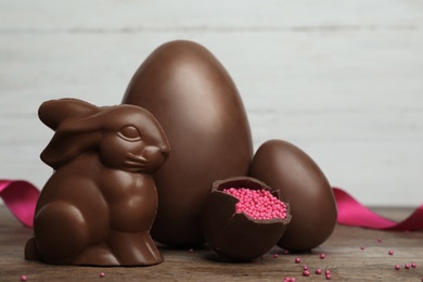 Photo of Composition with chocolate Easter eggs and bunny on table against light background