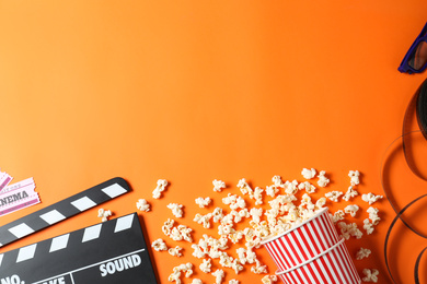 Photo of Flat lay composition with clapperboard and cinema tickets on orange background, space for text