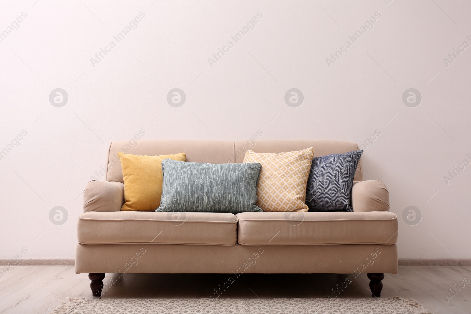 Photo of Comfortable beige sofa near light wall indoors, space for text. Simple interior