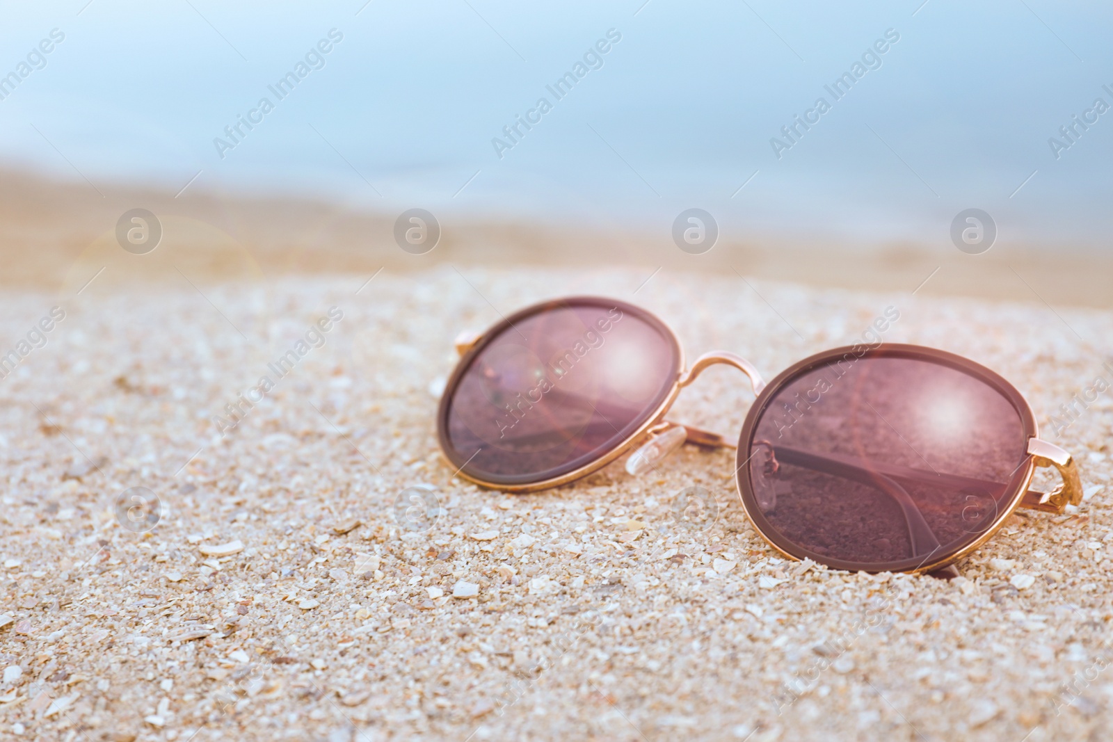 Photo of Stylish sunglasses on sandy beach near sea