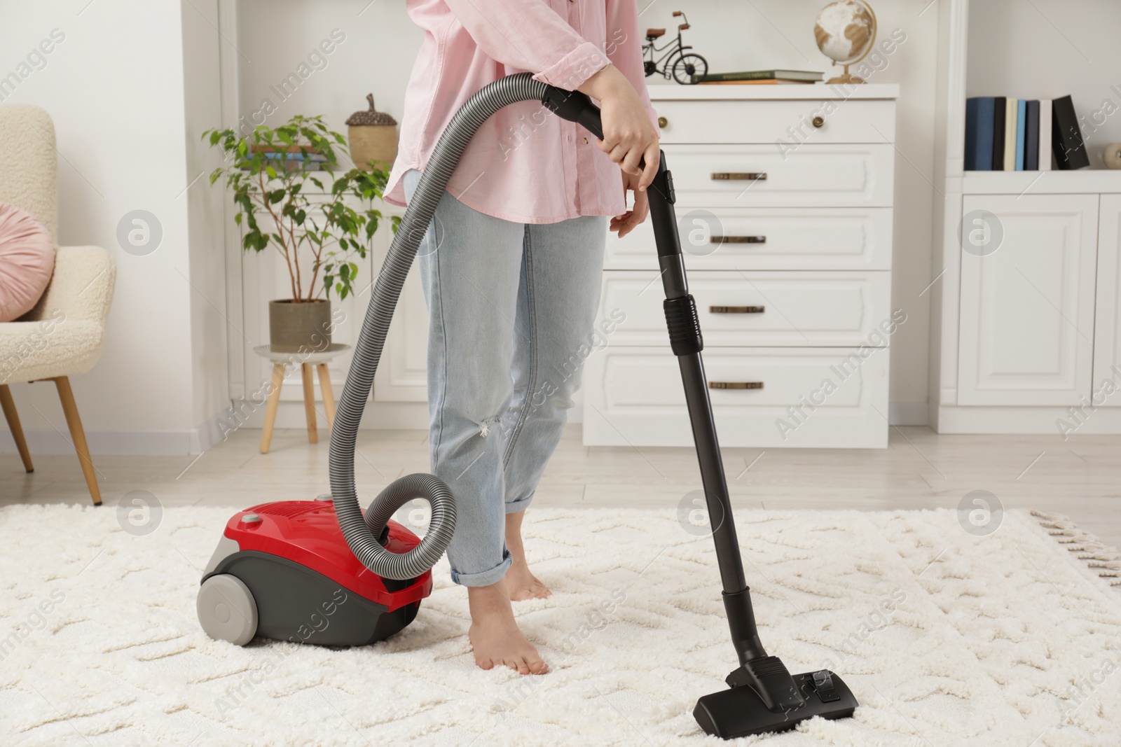 Photo of Woman cleaning carpet with vacuum cleaner at home, closeup