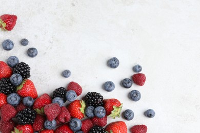 Many different fresh ripe berries on white textured table, flat lay. Space for text