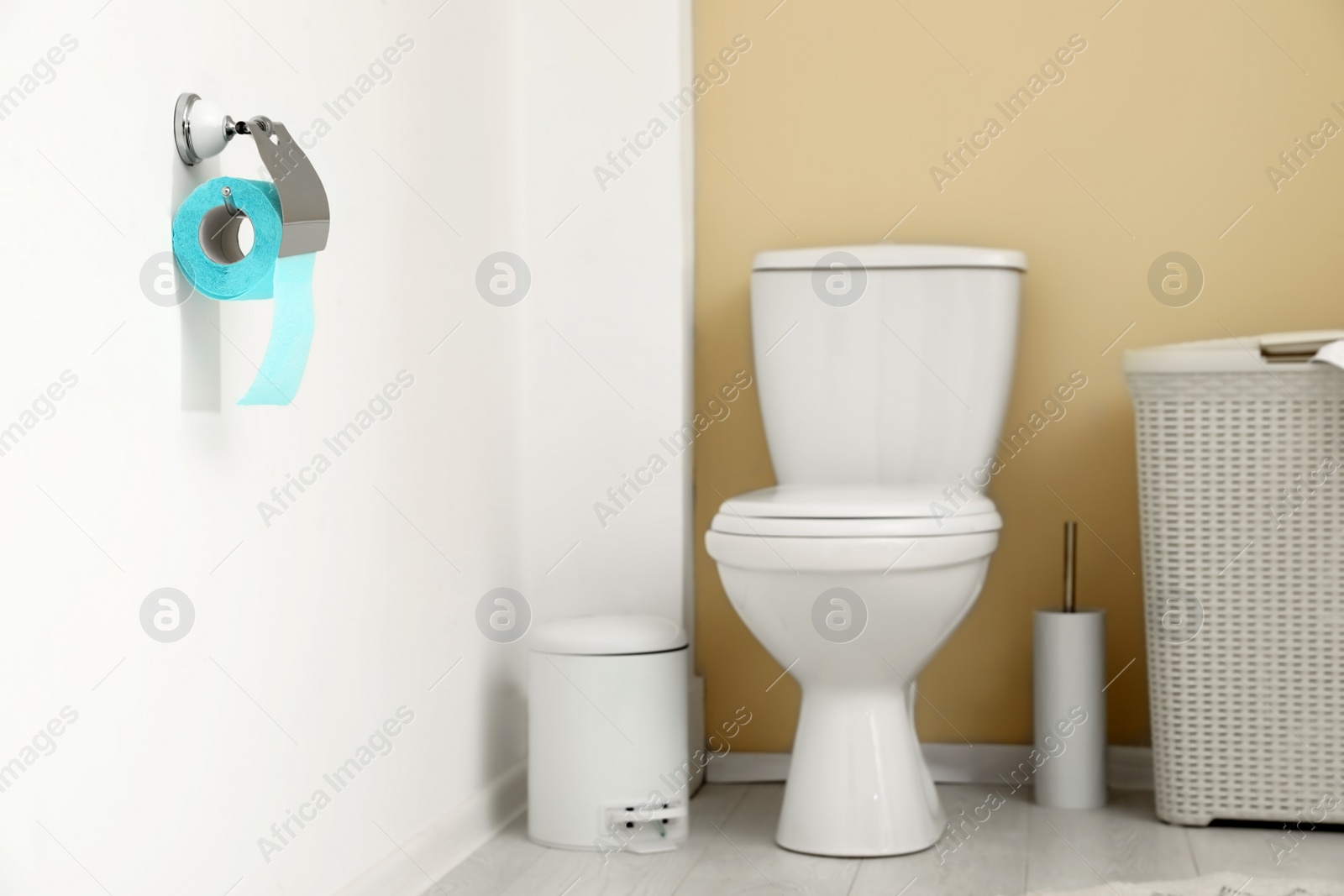 Photo of Holder with toilet paper roll on wall in bathroom