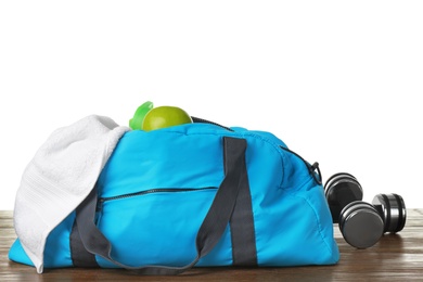 Photo of Sports bag and gym equipment on table against white background