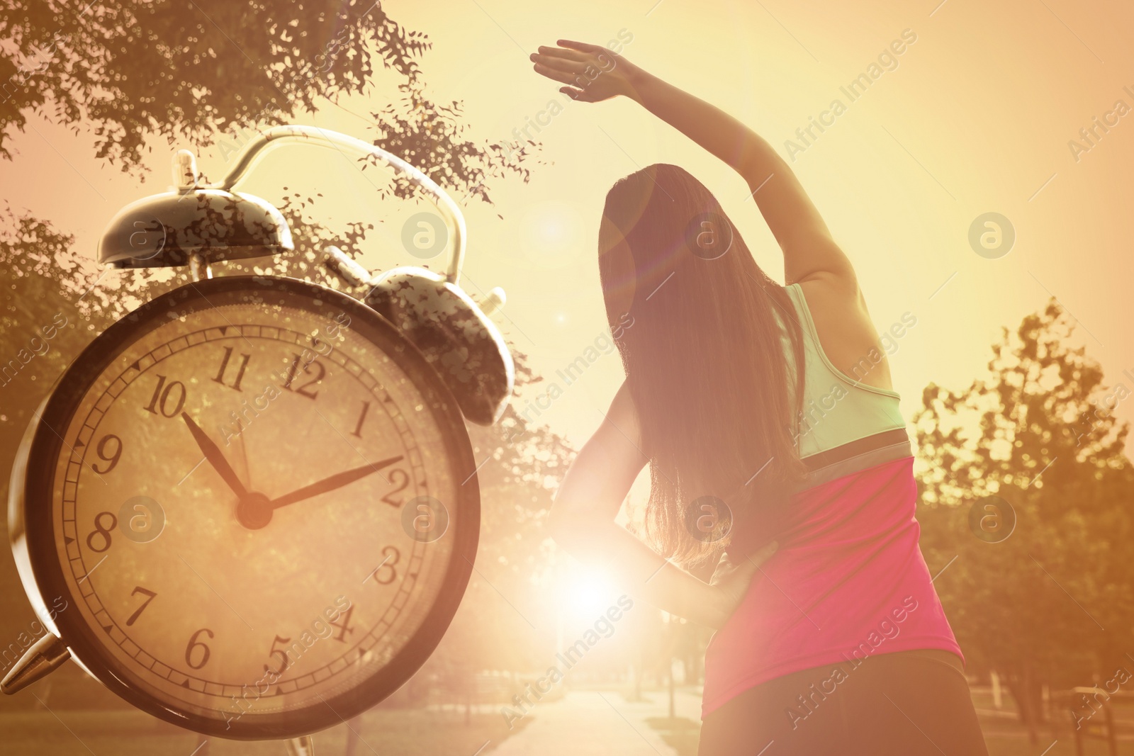 Image of Workout time. Double exposure of woman doing exercise on sunny morning in park and alarm clock