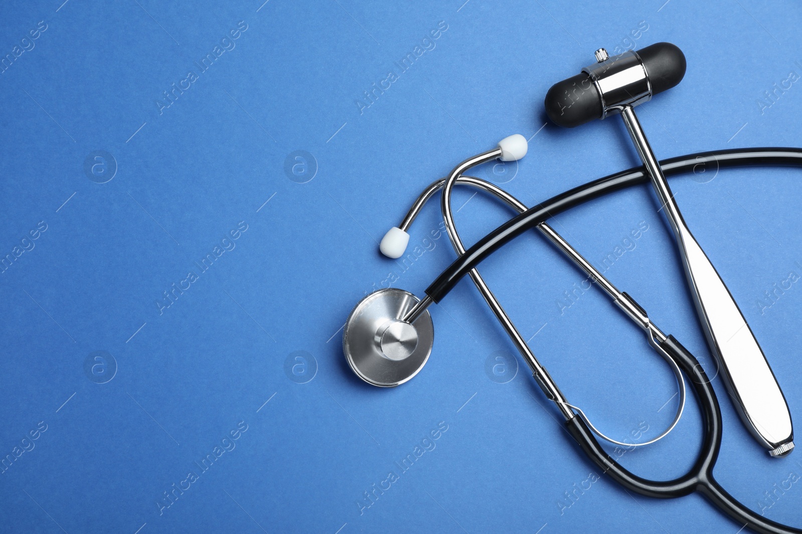 Photo of Reflex hammer, stethoscope and space for text on blue background, flat lay. Nervous system diagnostic