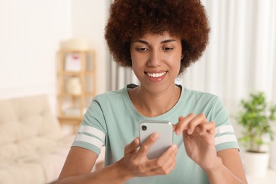 Photo of Happy young woman with smartphone in room