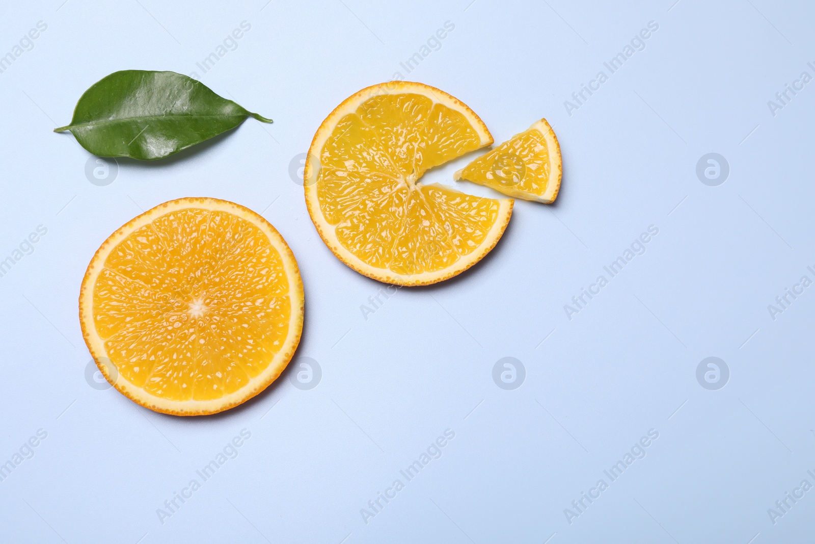 Photo of Slices of juicy orange and leaf on light blue background, top view. Space for text