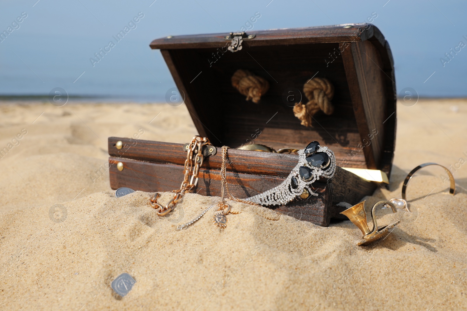 Photo of Open wooden treasure chest on sandy beach