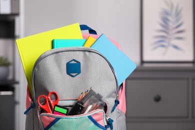 Photo of Children's backpack with different school stationery indoors, closeup. Space for text