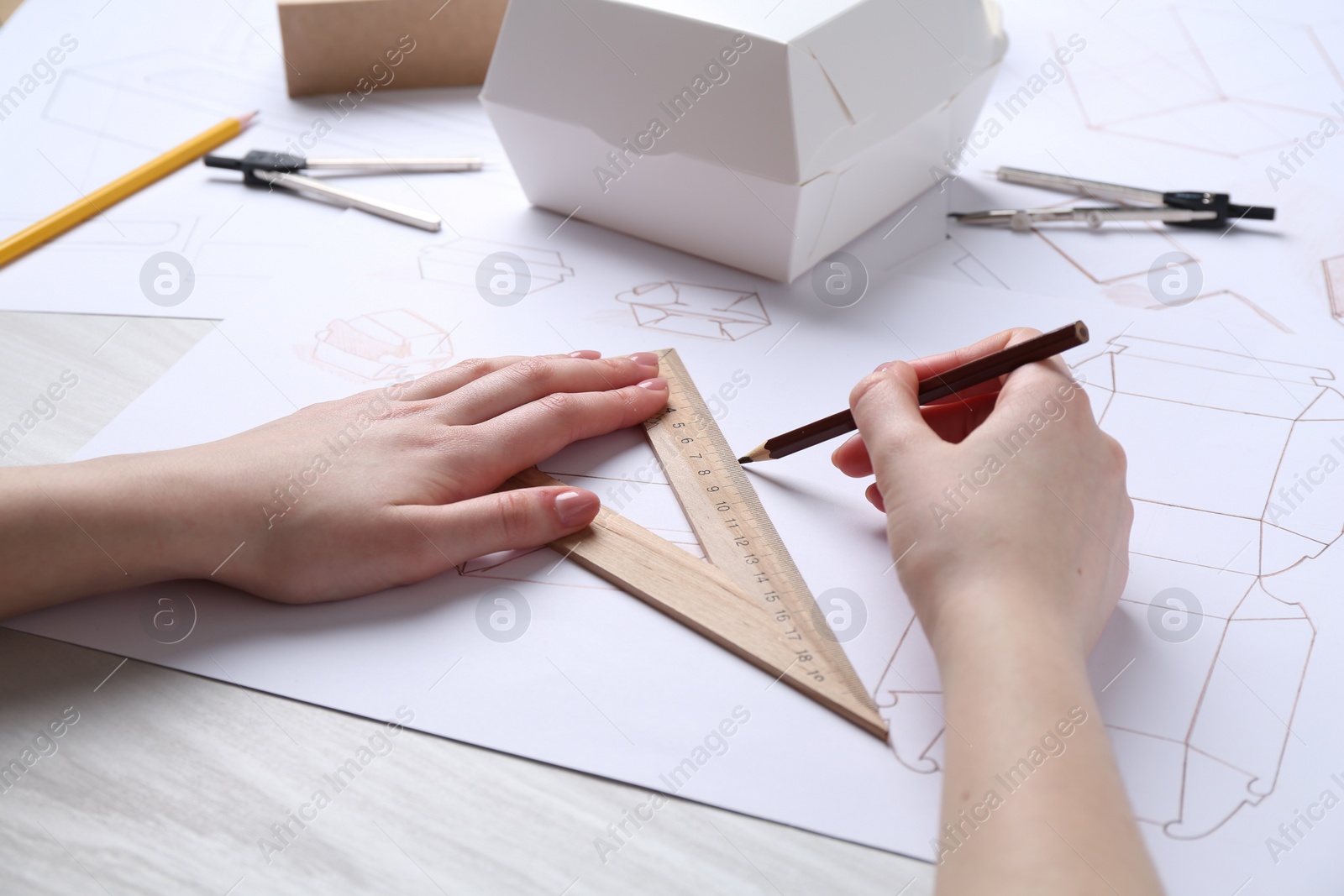 Photo of Woman creating packaging design at light wooden table, closeup