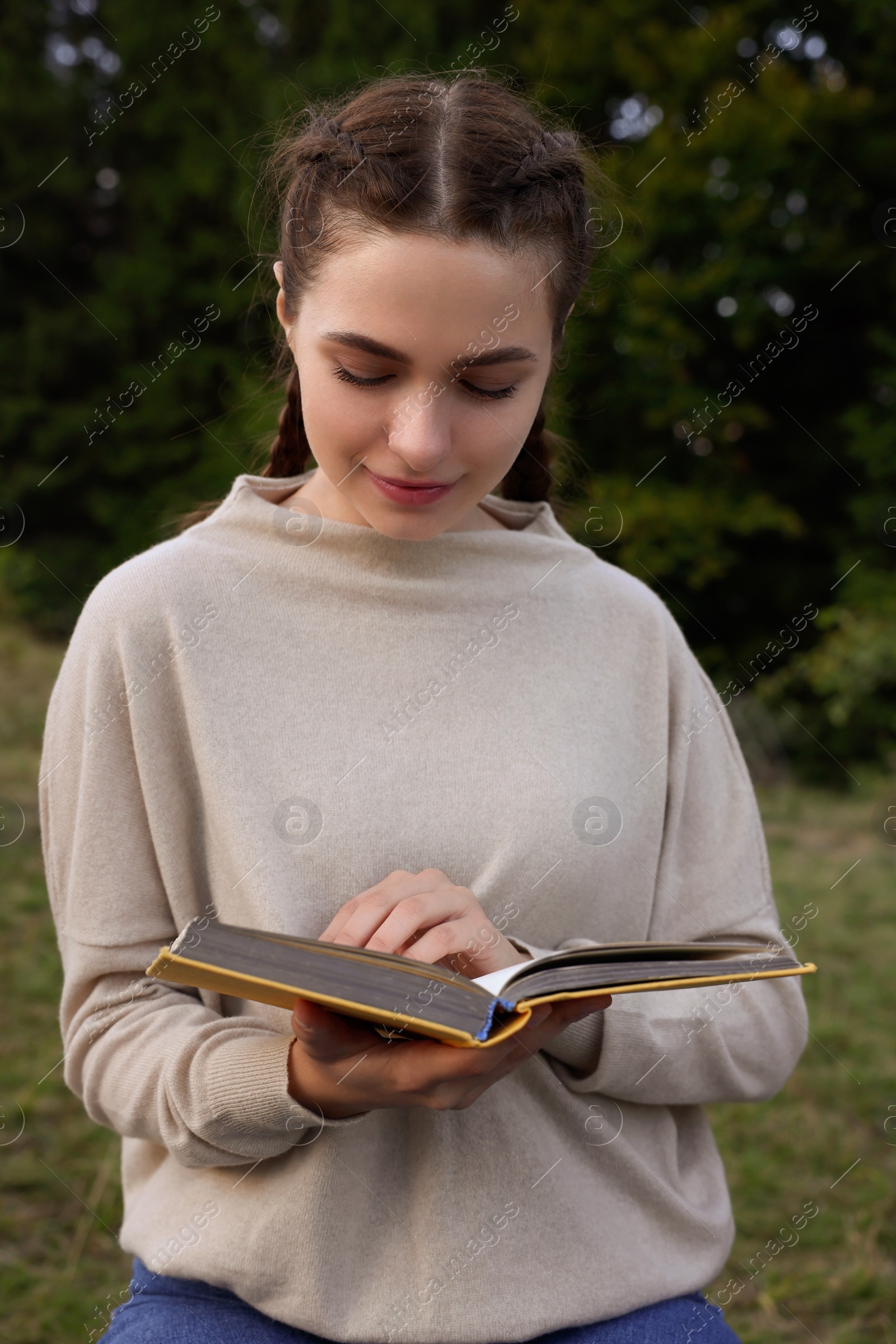 Photo of Beautiful young woman reading book in evening outdoors