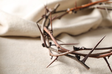 Photo of Crown of thorns on white fabric, closeup. Easter attribute