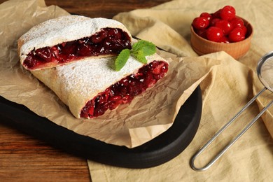 Delicious strudel with cherries on wooden table, closeup