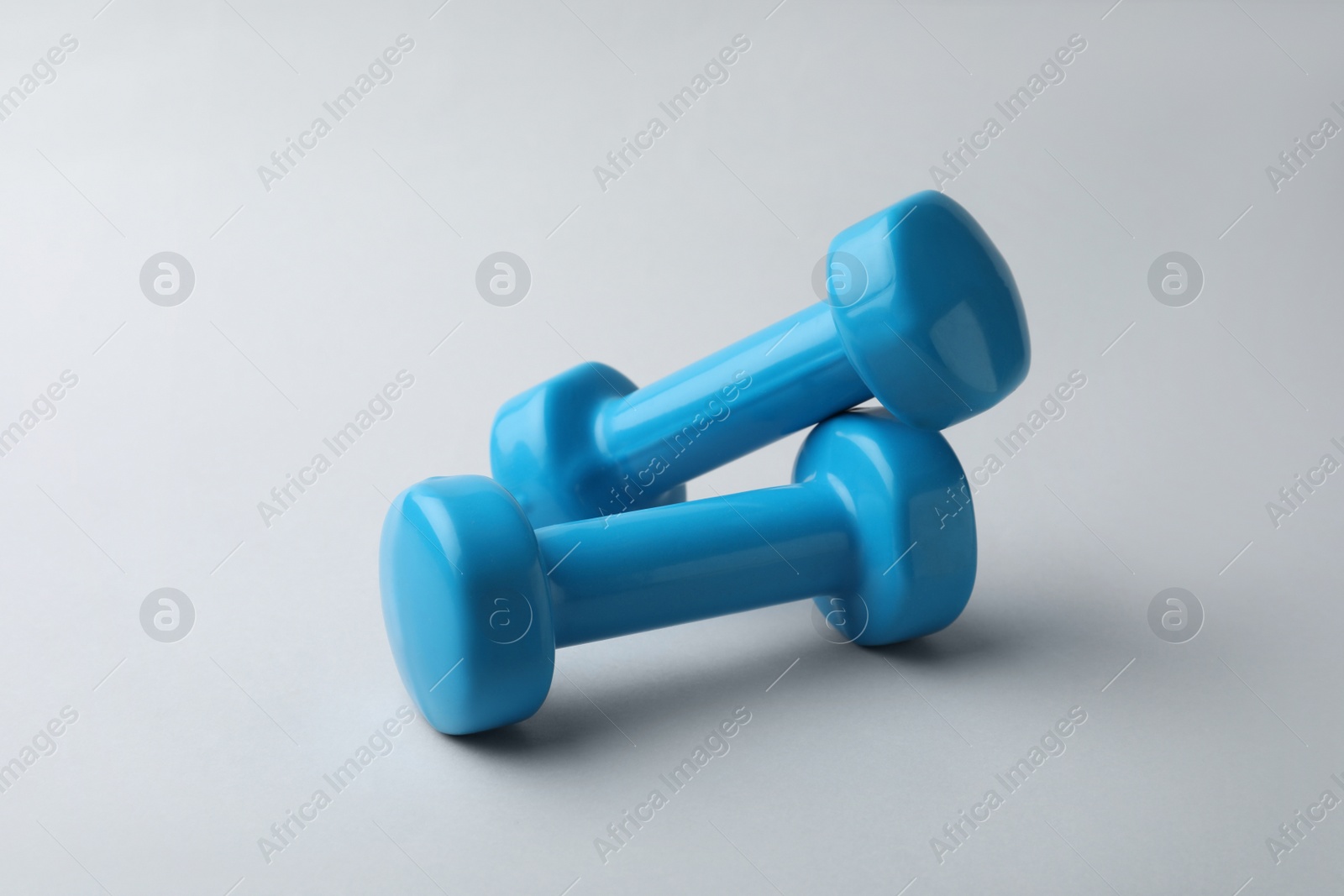 Photo of Two new blue vinyl dumbbells on light background