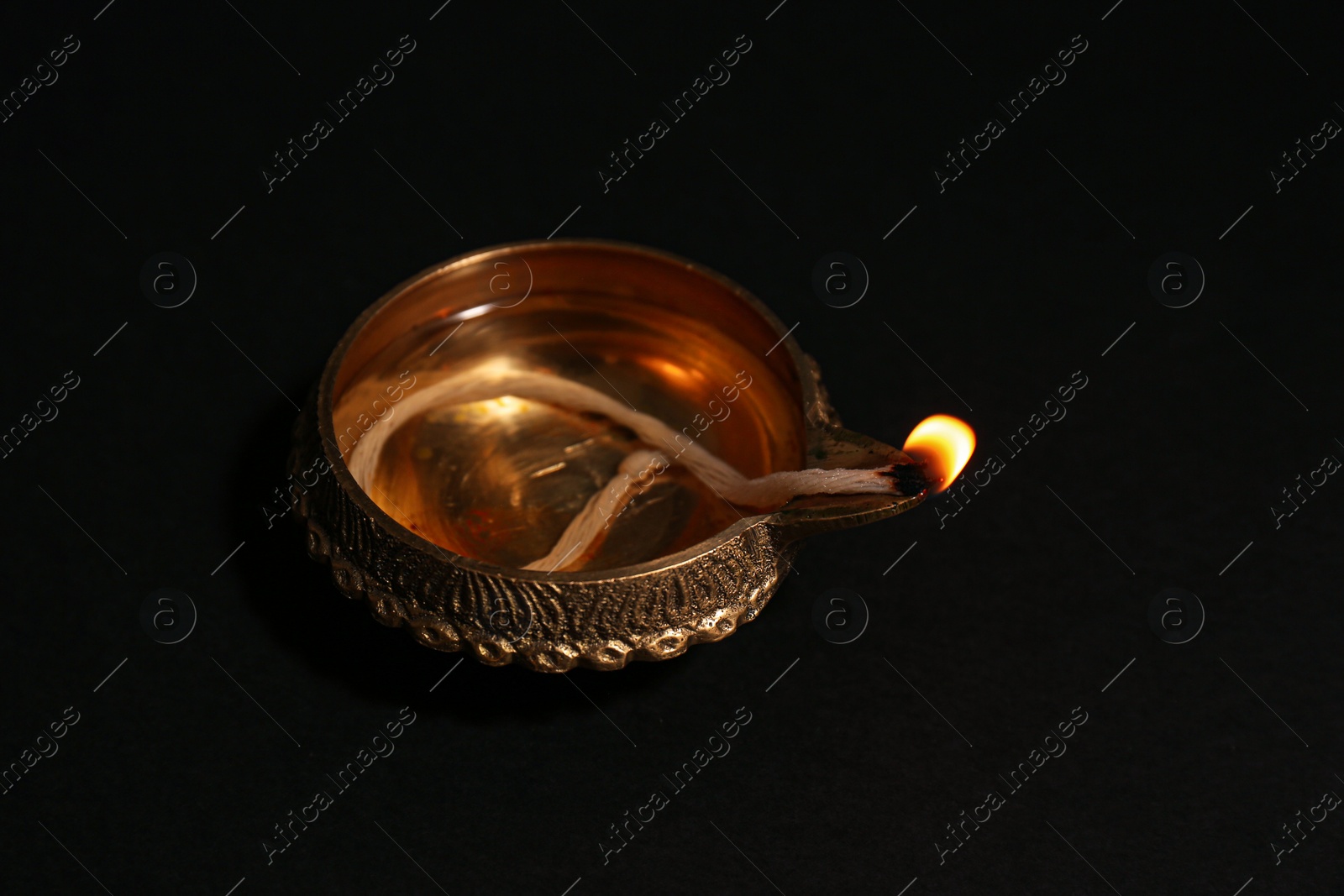 Photo of Lit diya on dark background, closeup. Diwali lamp