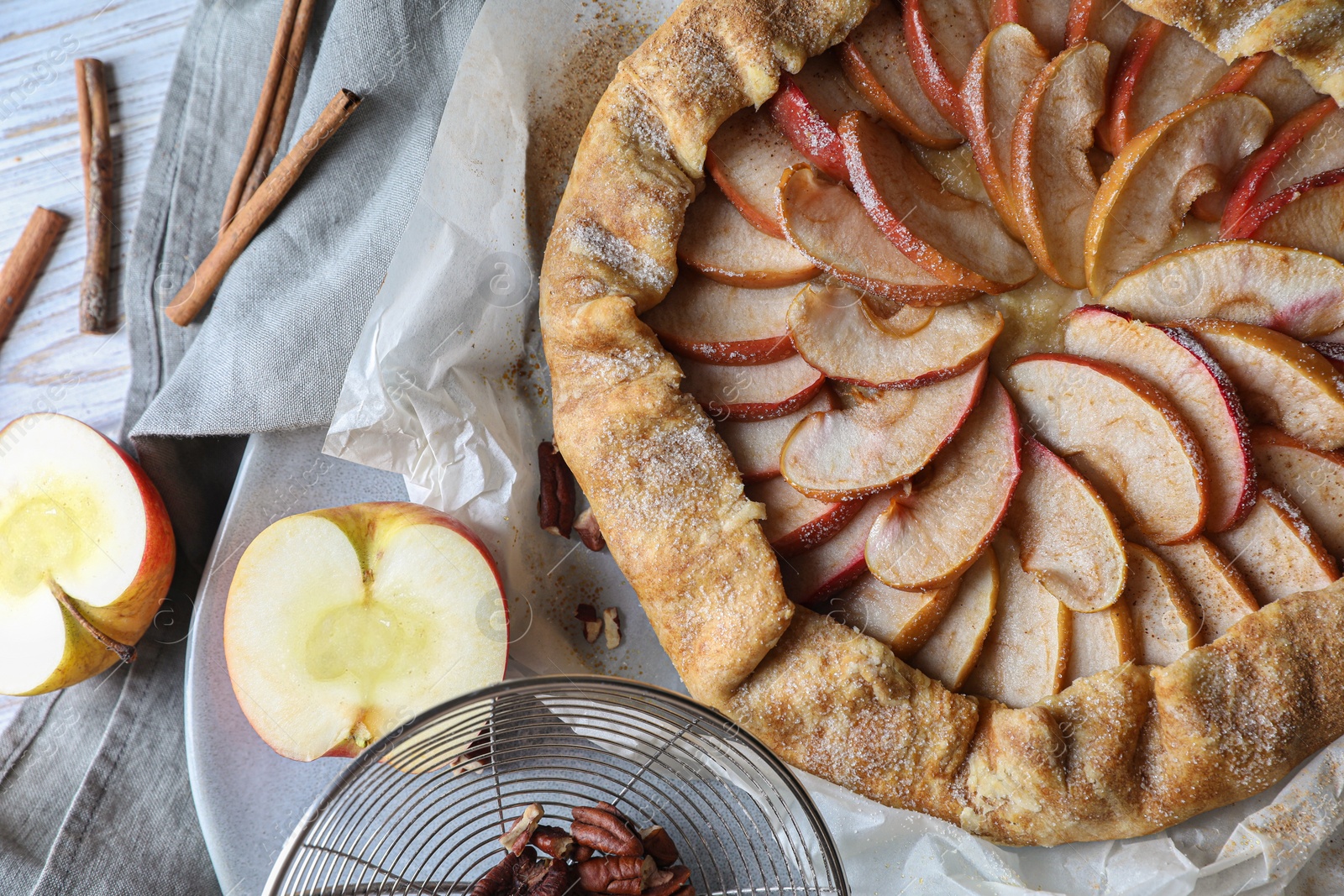 Photo of Delicious apple galette, cinnamon and pecans on table, flat lay