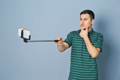 Young handsome man taking selfie against grey background