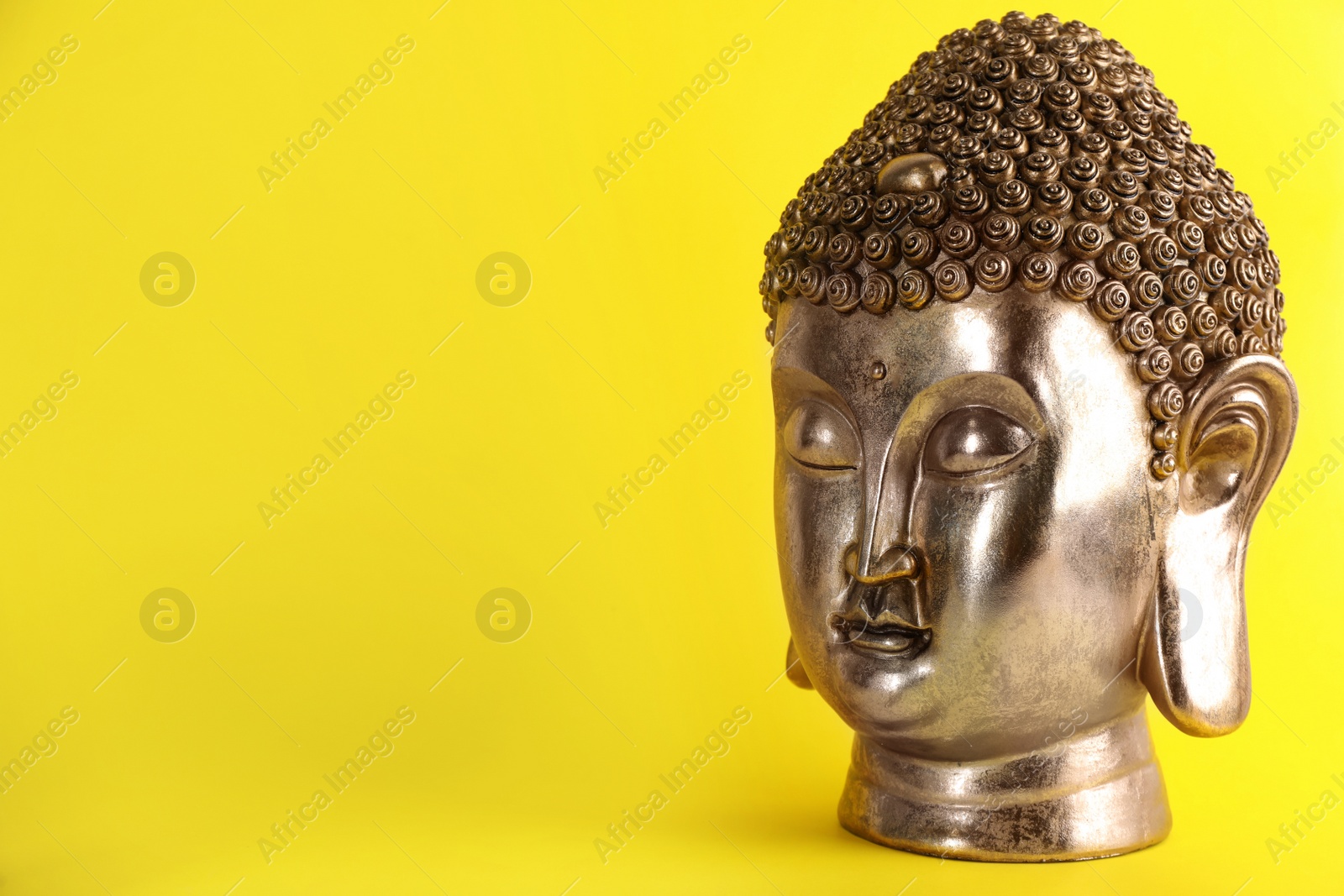 Photo of Beautiful golden Buddha sculpture on yellow background. Space for text