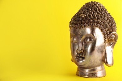 Photo of Beautiful golden Buddha sculpture on yellow background. Space for text