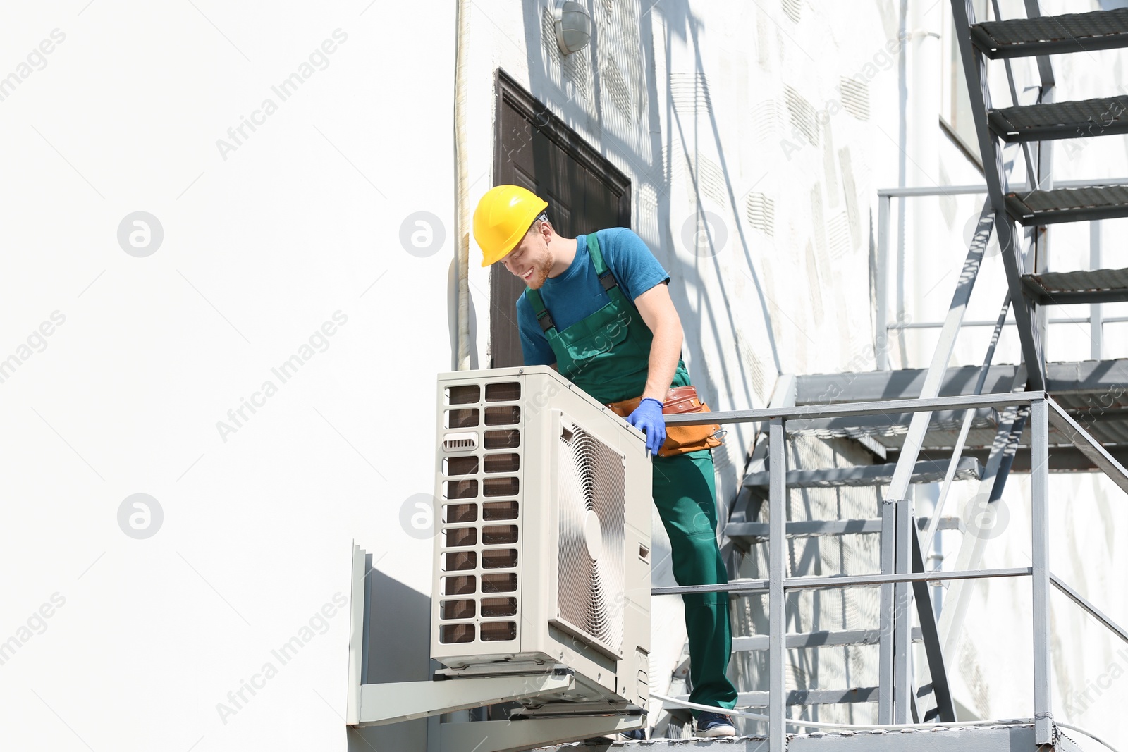 Photo of Professional technician repairing modern air conditioner outdoors