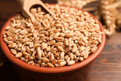 Photo of Bowl of wheat grains on wooden table, closeup