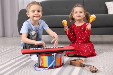 Little children playing toy musical instruments at home