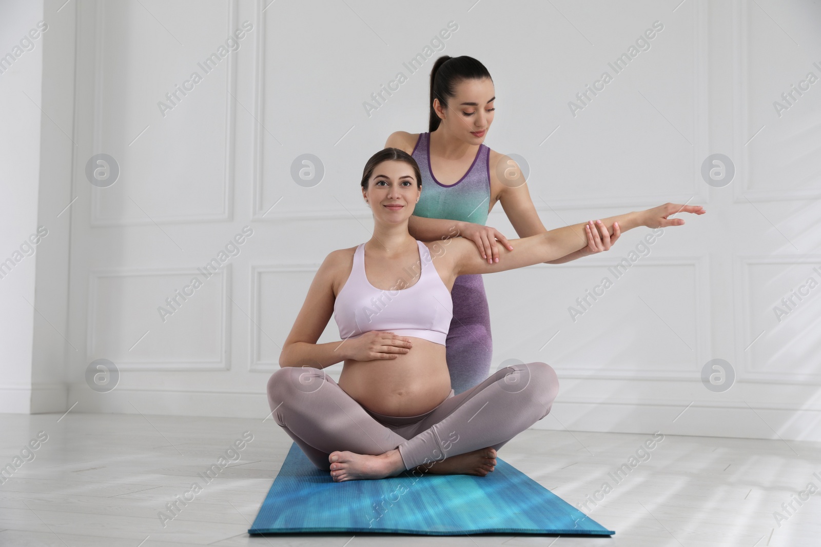 Photo of Trainer working with pregnant woman in gym. Preparation for child birth