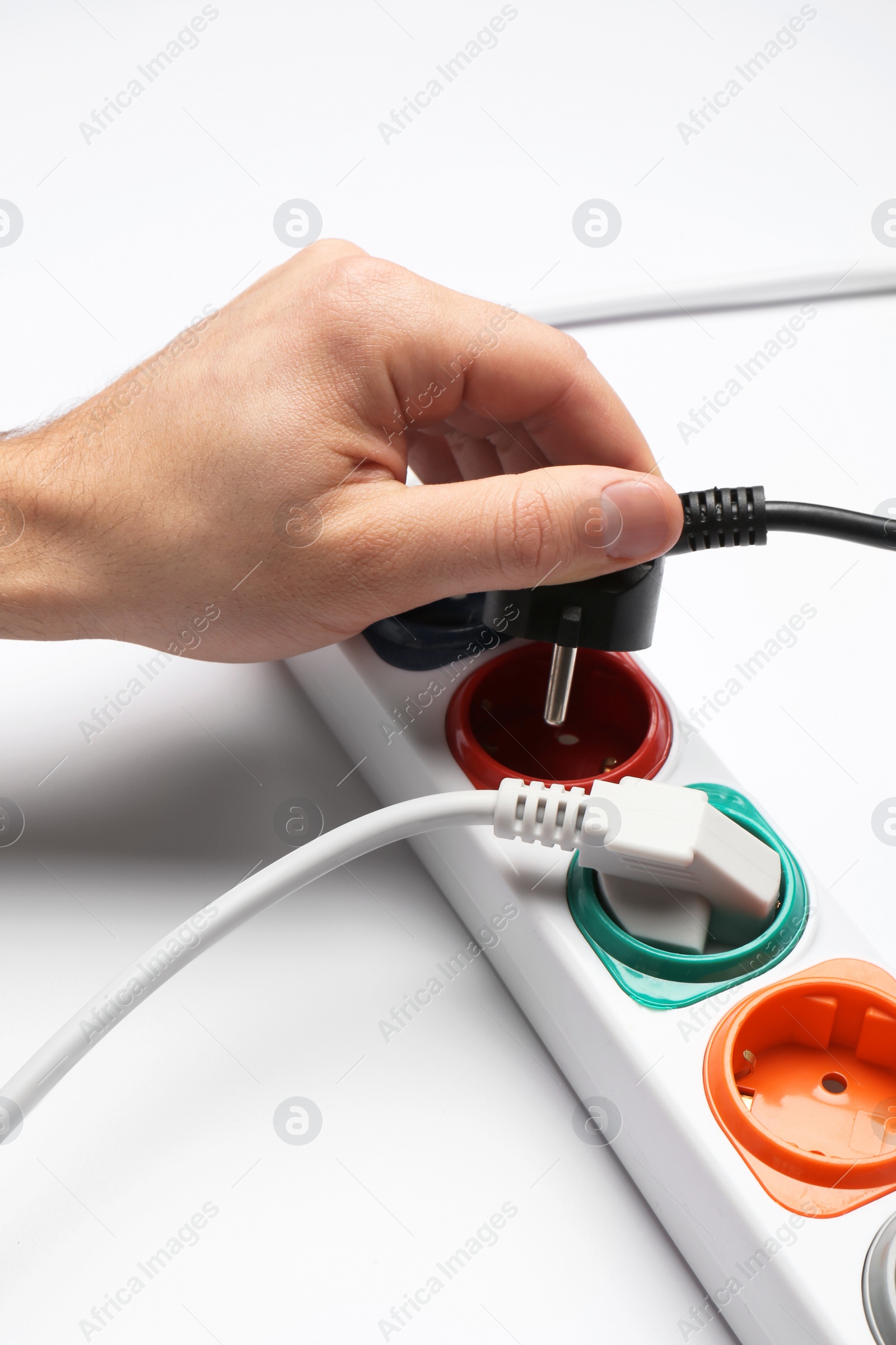 Photo of Man inserting power plug into extension cord on white background, closeup. Electrician's professional equipment