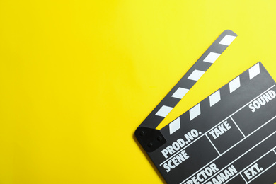 Photo of Clapper board on yellow background, top view with space for text. Cinema production