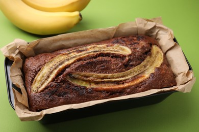 Photo of Delicious banana bread and fresh fruits on green background, closeup