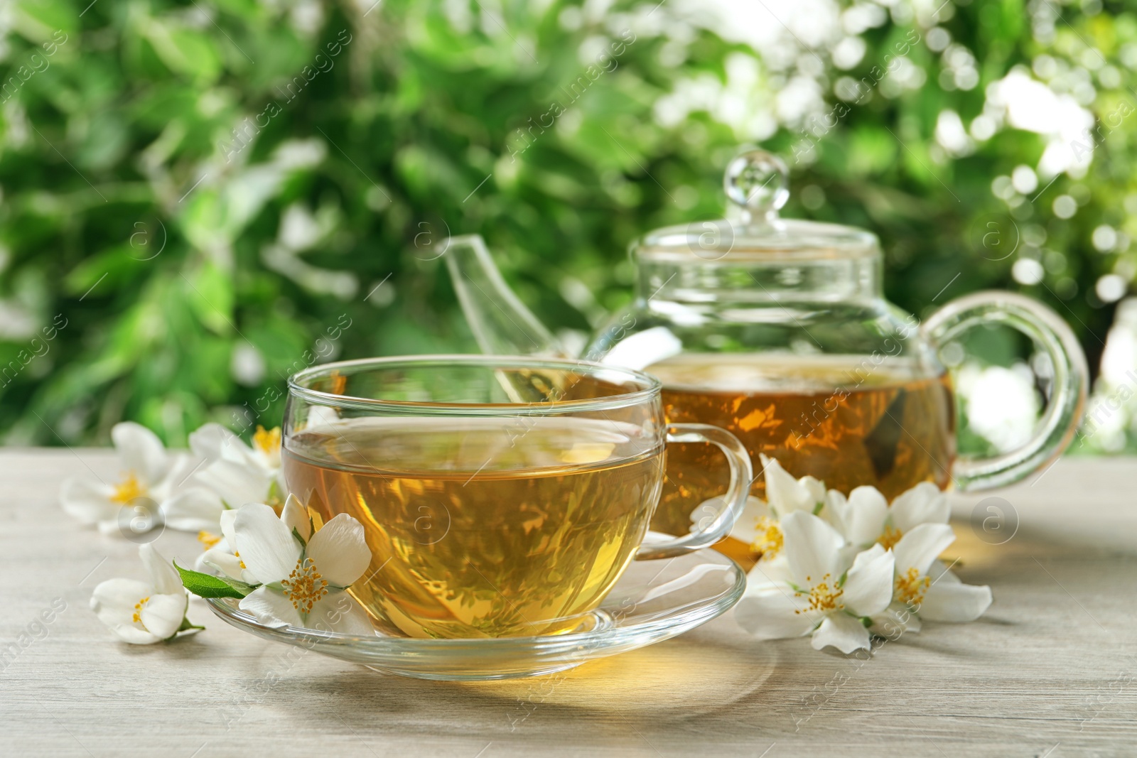 Photo of Aromatic jasmine tea and fresh flowers on wooden table