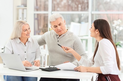 Photo of Mature couple discussing pension with consultant in office