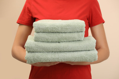 Photo of Woman holding fresh towels on color background, closeup