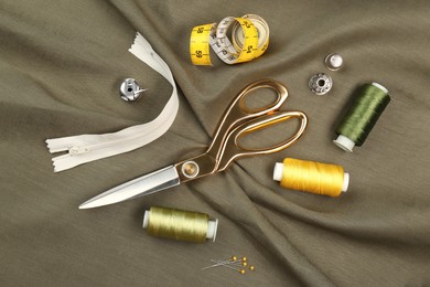 Photo of Different sewing supplies on grey fabric, flat lay