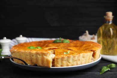 Delicious meat pie with basil on black table. Space for text