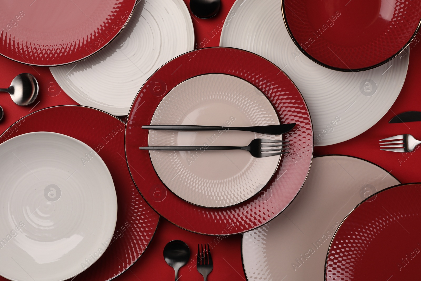 Photo of Stylish table setting with cutlery on red background, flat lay