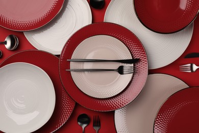 Stylish table setting with cutlery on red background, flat lay