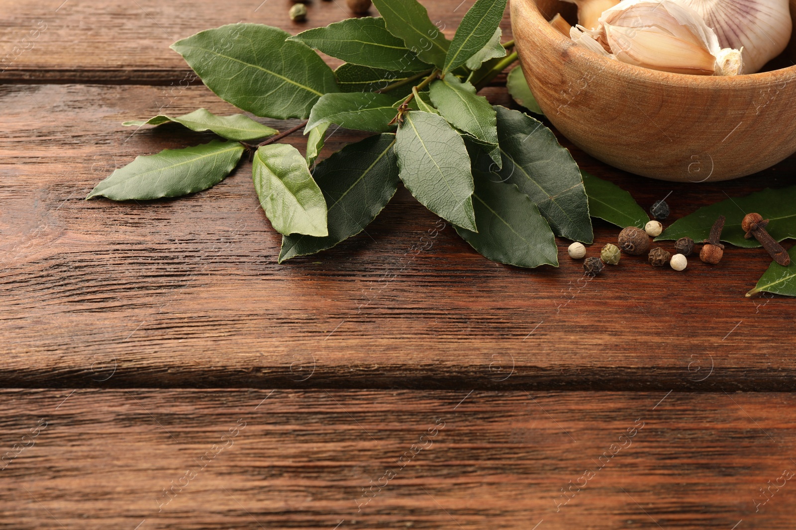 Photo of Aromatic fresh bay leaves and spices on wooden table, space for text