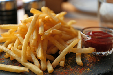 Tasty French fries with red sauce served on table in cafe, closeup