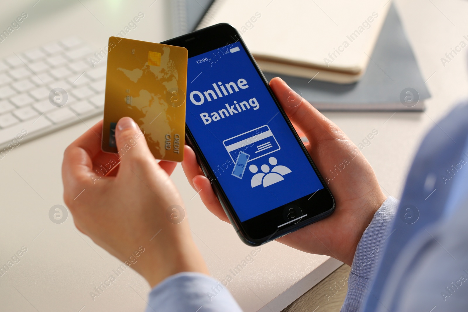 Photo of Woman using online banking app on smartphone and credit card at white office table, closeup